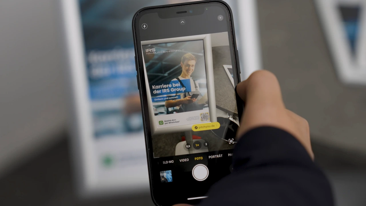 IRS Intelligent Repairs – Smartphone mit dem Karriereplakat der IRS Group